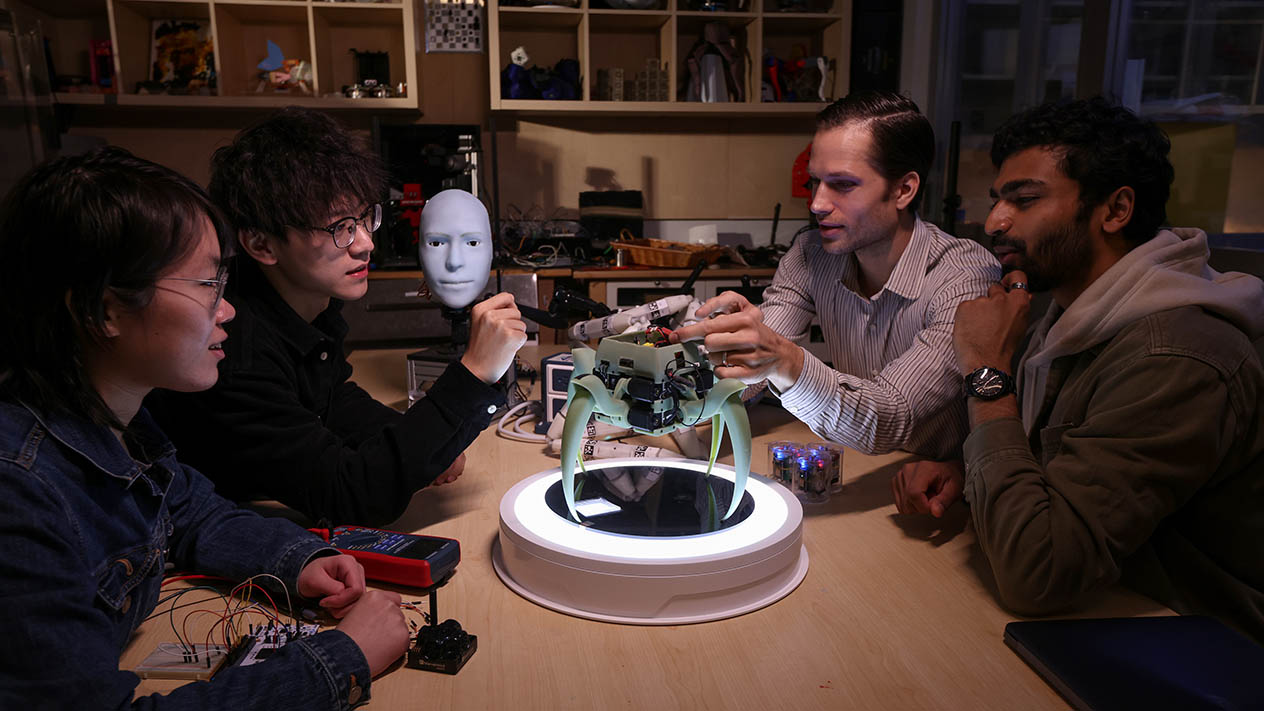 Four Columbia Engineering students working together on a robotics project.