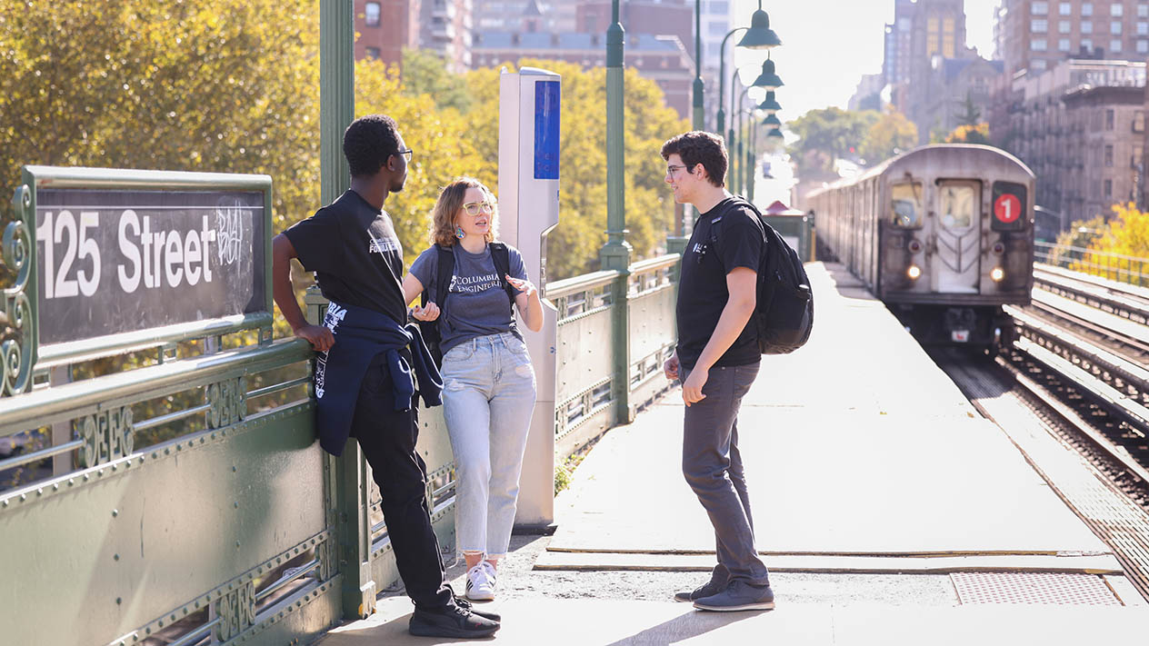 Three Columbia University students standing at a New York City train station.